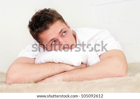 Beautiful Caucasian man lying on a rug on a light background