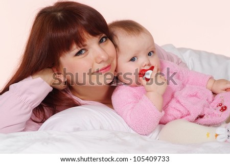 A Caucasian mom with her daughter lying in bed on a light background
