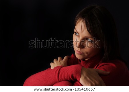 Happy sad Caucasian female sitting on a dark background