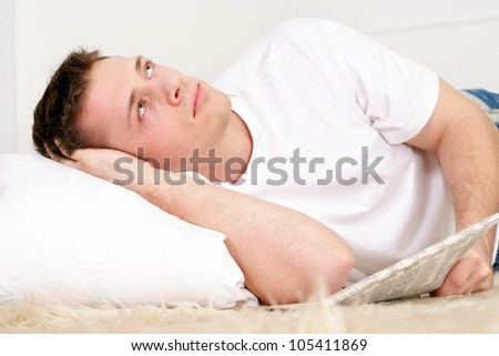 Beautiful nice man lying on the mat with the paper on a light background