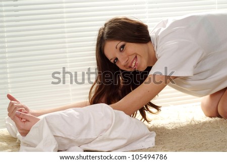 A pretty caucasian girl stretches on the carpet against the window