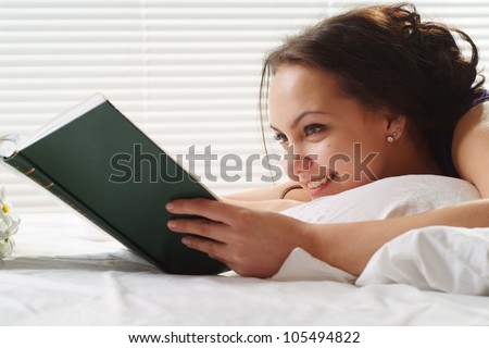 Luck Caucasian woman lying in a bed of book on a light background