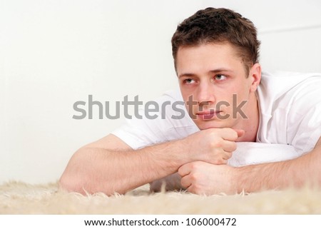 Beautiful man lying on a rug on a light background