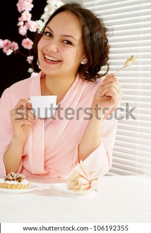 A luck caucasian woman sitting at the table with a cake on a light background