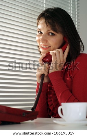 Caucasian woman sitting with a phone on a light background