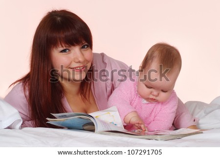 A happy Caucasian mother with her daughter lying in bed on a light background