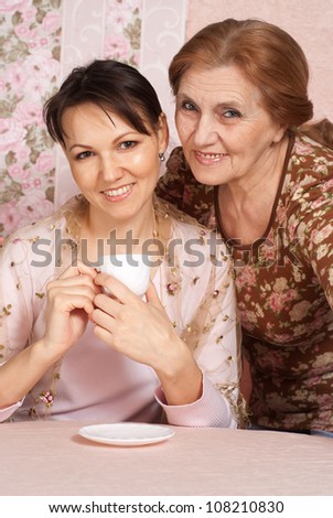 Beautiful older woman in a blouse with flowers and her daughter