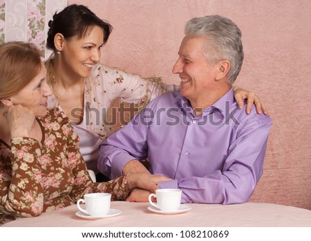 Beautiful older woman in a blouse with flowers, her husband and daughter