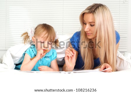 Nice caucasian mother and daughter lying on the bed with a pencils