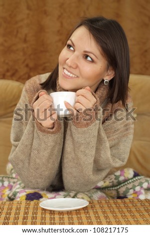 Beautiful luck Caucasian woman sitting on a sofa on a brown background