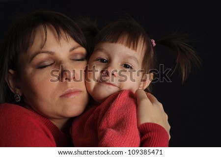 Happy sad Caucasian mother with a daughter on a dark background