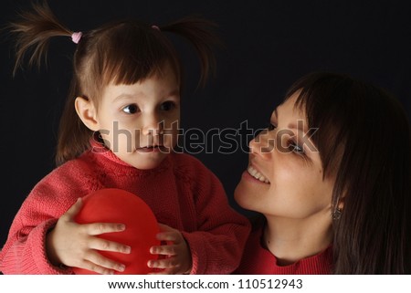 Happy Caucasian happy mom with a daughter and an air ball on a dark background
