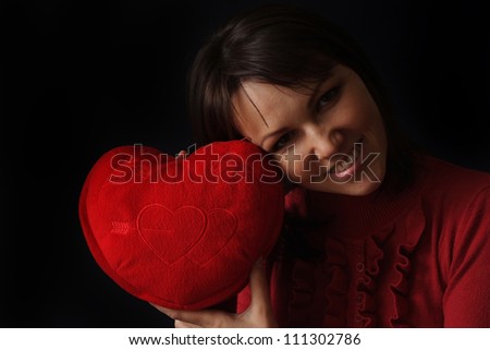 Happy Caucasian woman with a happy heart pillow on a dark background
