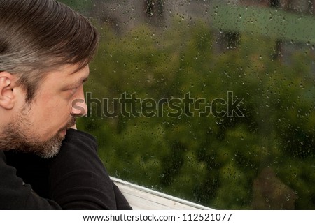 Interesting man sitting in a room at home in front of the window