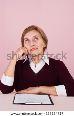 Good old Caucasian business woman sitting  whith a staff on a pink background