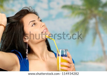 portrait of a beautiful young woman with juice on a blue