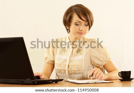 Portrait of a nice young woman with a laptop on a beige background