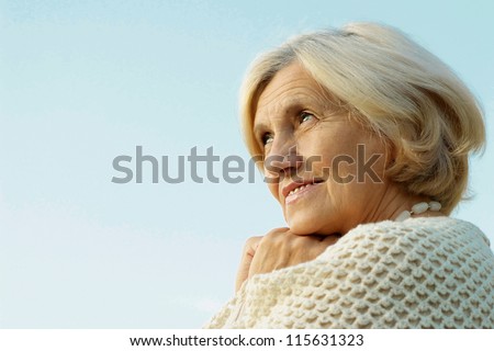 Happy elderly woman posing against the sky