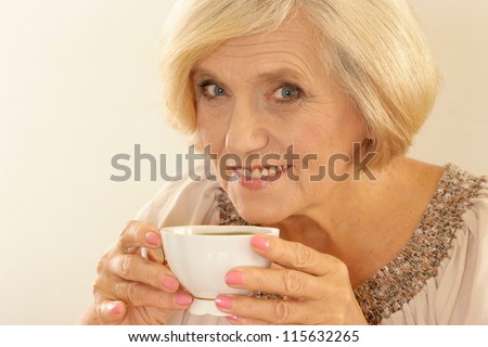 portrait of a happy old woman with tea on a beige