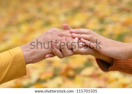 hands of people of different ages in the autumn park