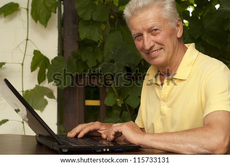 Beauteous older man sitting at a table at home on the veranda