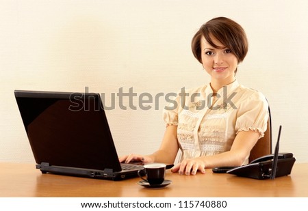 Portrait of a nice young girl with a laptop on a beige background