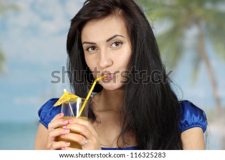 portrait of a beautiful young woman with juice on a blue background