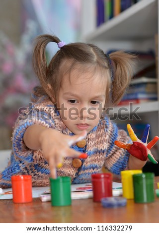 Portrait of a cute child draws paints in the room