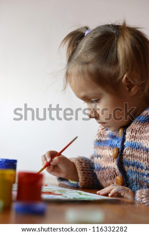 portrait of a cute baby draws paint