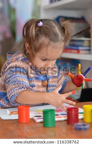 Portrait of a cute child draws paints at the table