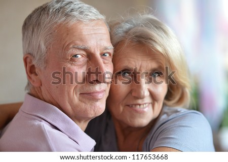 happy good-looking elderly couple posing in the room