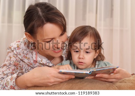 Little girl and mom sitting at a table with a book