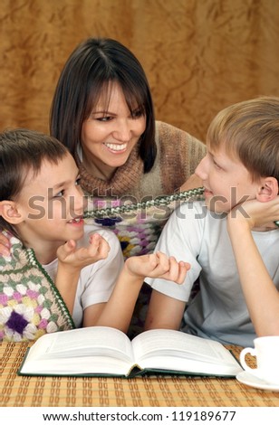 kids and mom sitting at a table with a book