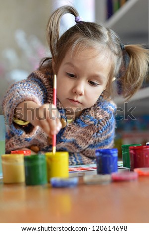 beautiful baby draws paint in the room