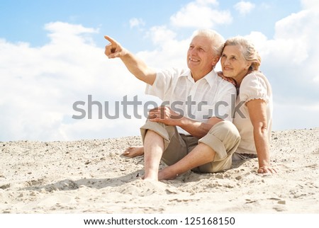Amusing elderly couple went to the beach to enjoy the sea breeze