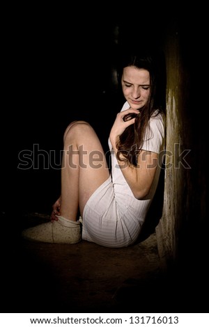 Portrait of a frightened teenage girl in a dark cellar