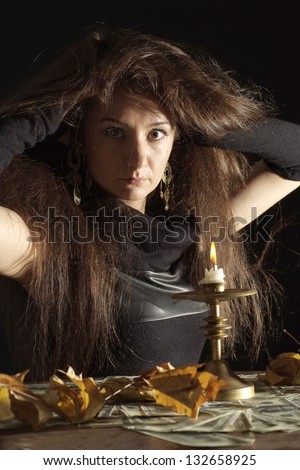 Pleasant girl as a witch on a dark background