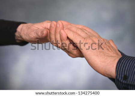 Concept shoot of friendship and love of man and woman: two hands over gray background