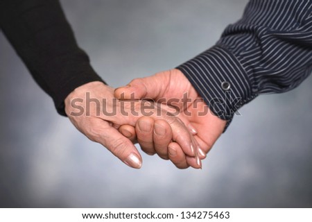 Concept shoot of friendship and love of man and woman: two hands over gray background