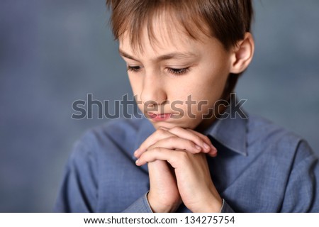 portrait of a thinking little boy over a gray background