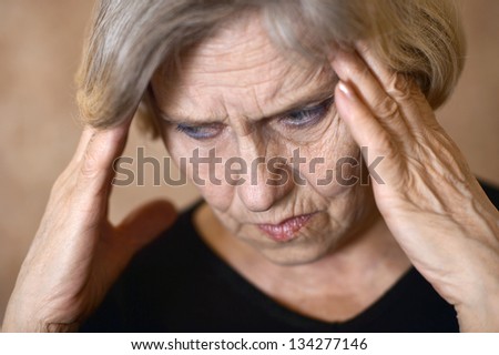 portrait of an older woman with a headache on a beige background
