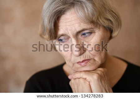 portrait of melancholy older woman on a beige background