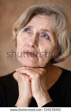 portrait of melancholy older woman on a beige background