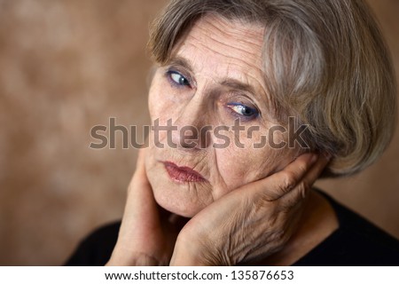 close-up portrait of a sad older woman on a beige background