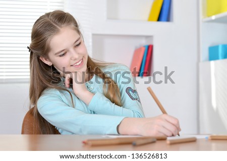 Young cute girl drawing at the table at home