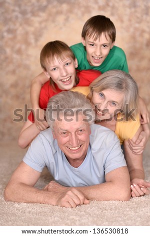 Happy elderly couple and their grandchildren are lying on the floor