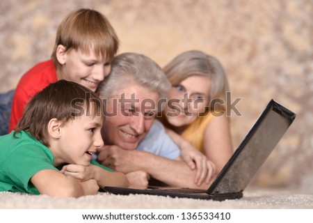 elderly couple and their grandchildren resting at a laptop