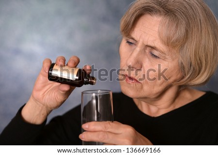 elderly caucasian woman treated by medicines on a gray background