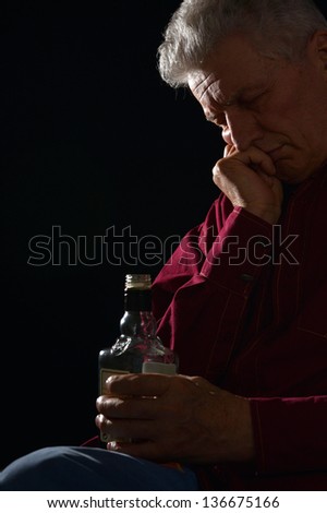 lonely old man drinking alcohol on a black background