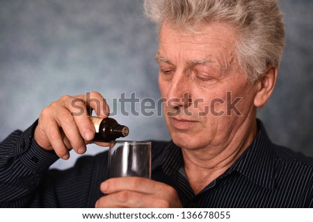 elderly man treated by medicines on a gray background